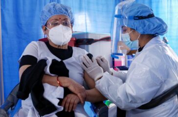 A paramedic administers booster dosage of anti-COVID vaccine at Patan Hospital