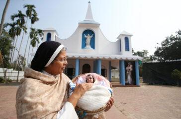 A nun holding a statue of baby Jesus on the eve of Christmas celebrations