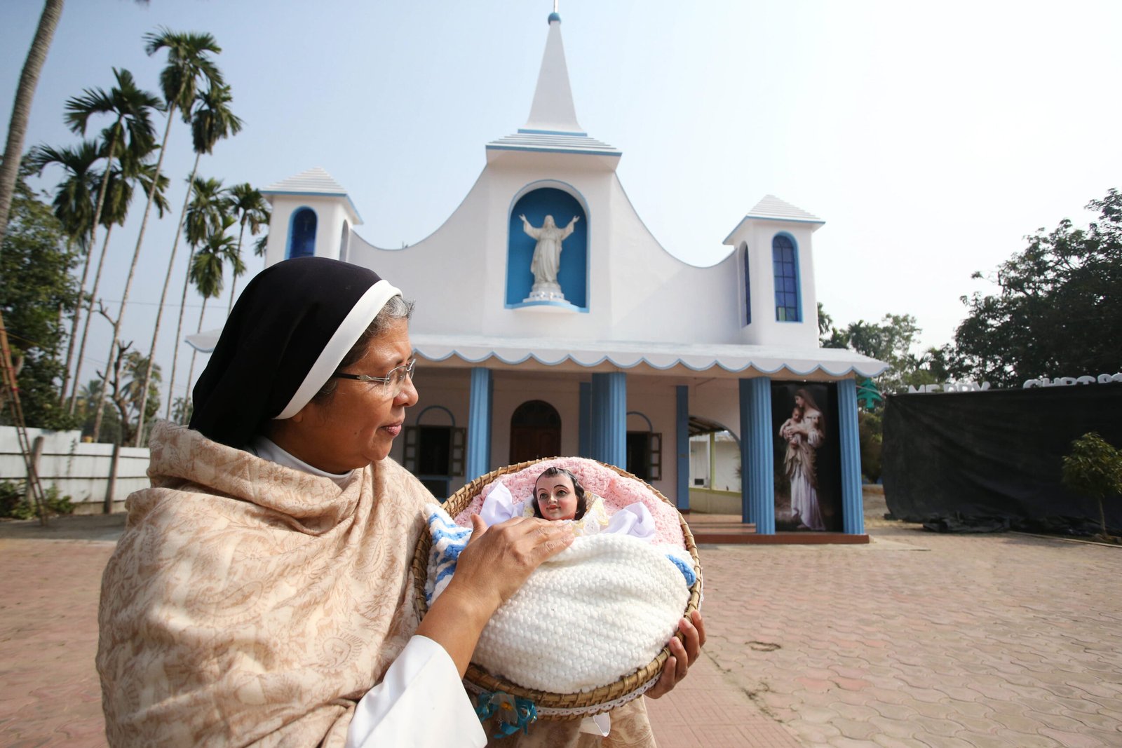 A nun holding a statue of baby Jesus on the eve of Christmas celebrations