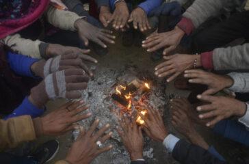 People sit around a bonfire to warm themselves on a cold winter day